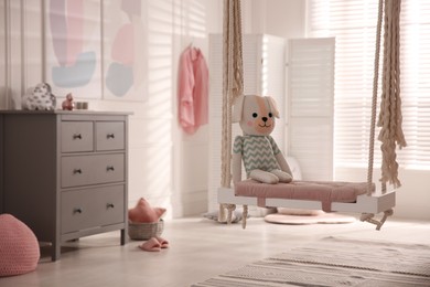 Beautiful swing with toy dog in room. Stylish interior design