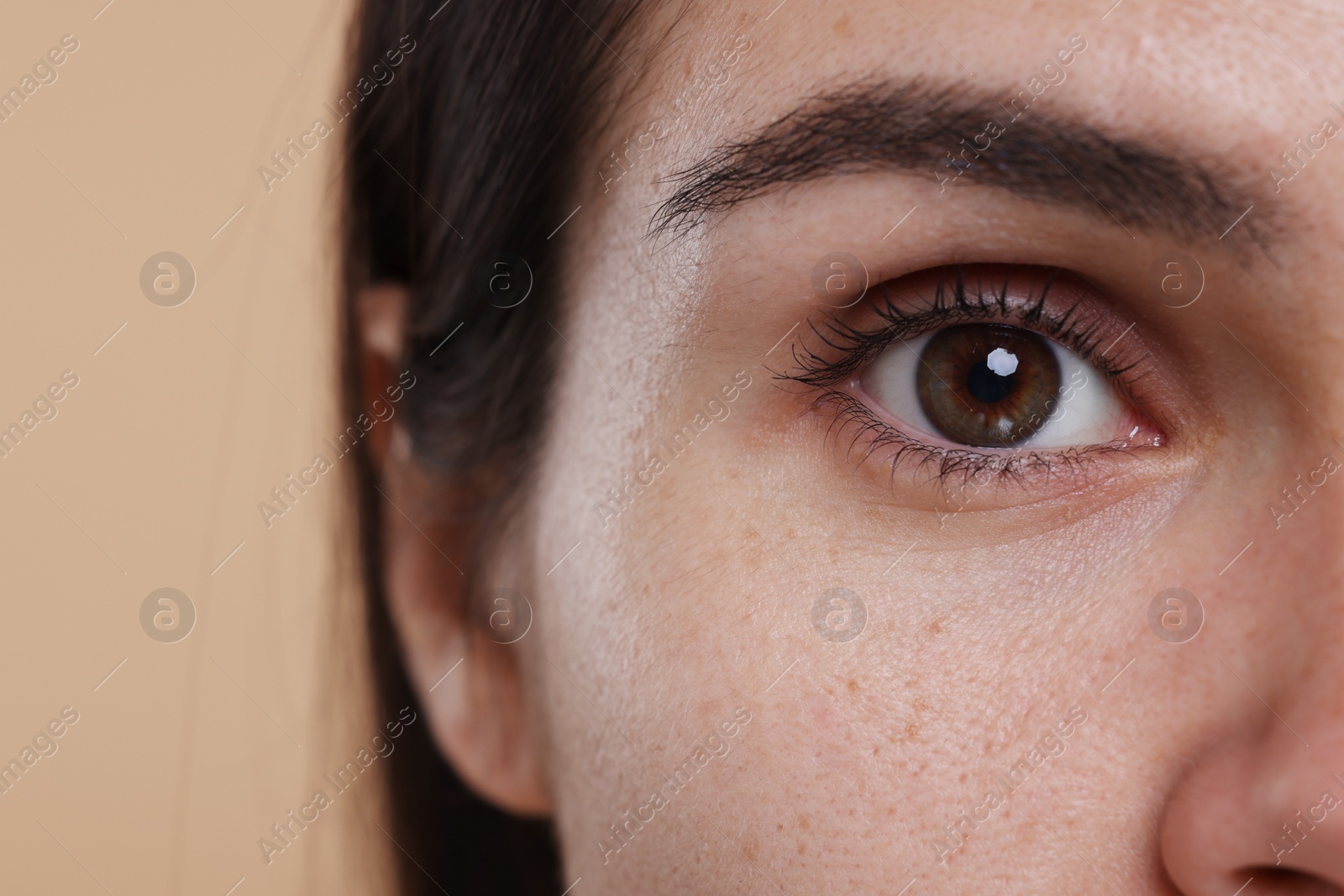Photo of Closeup view of woman with beautiful hazel eyes on beige background