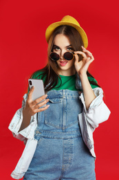 Beautiful woman with mobile phone on red background