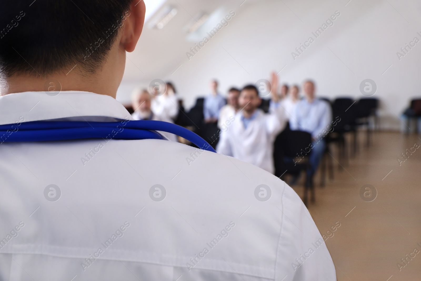 Photo of Doctor having discussion with audience in meeting room during medical conference, closeup