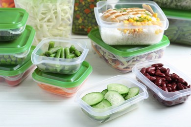 Photo of Set of plastic containers with fresh food on white wooden table