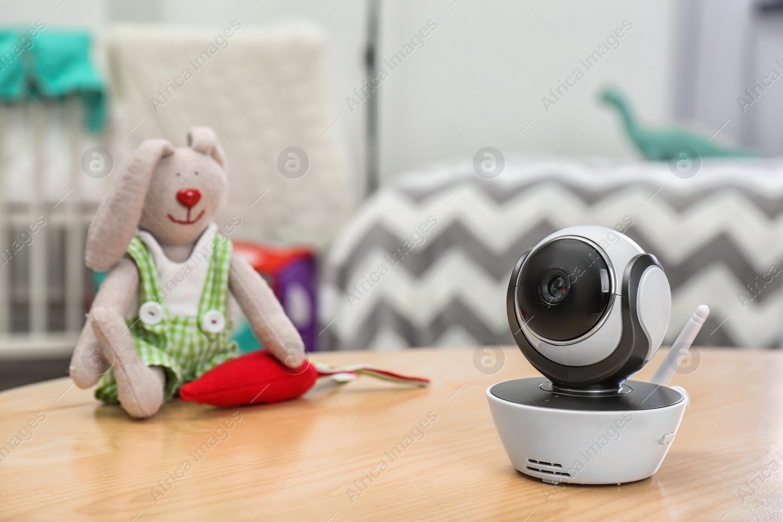 Photo of Baby monitor and toy on table in room, space for text. CCTV equipment