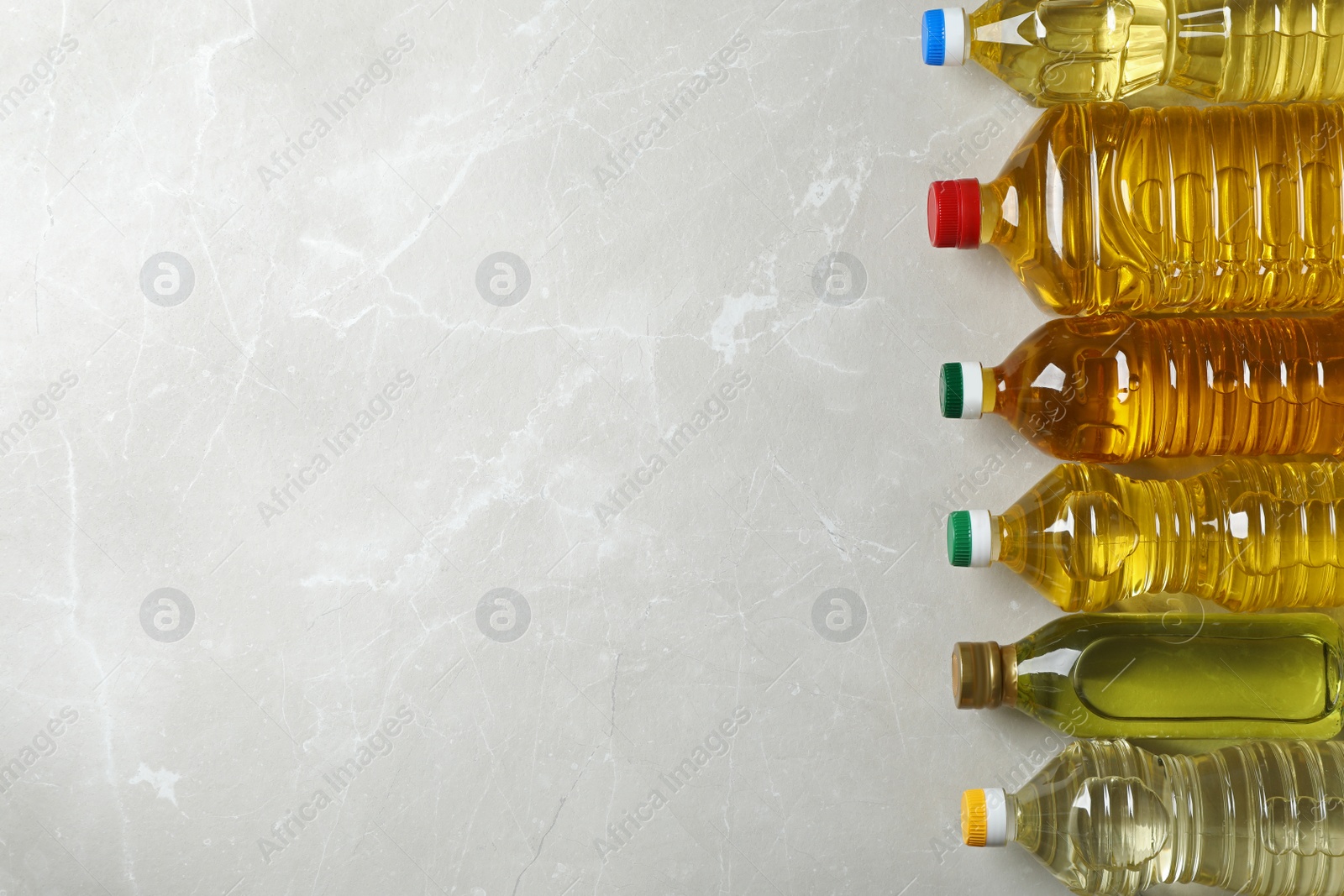 Photo of Bottles of oils and space for text on light background, top view