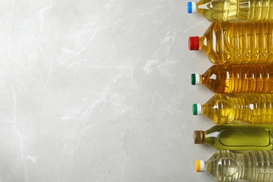 Bottles of oils and space for text on light background, top view