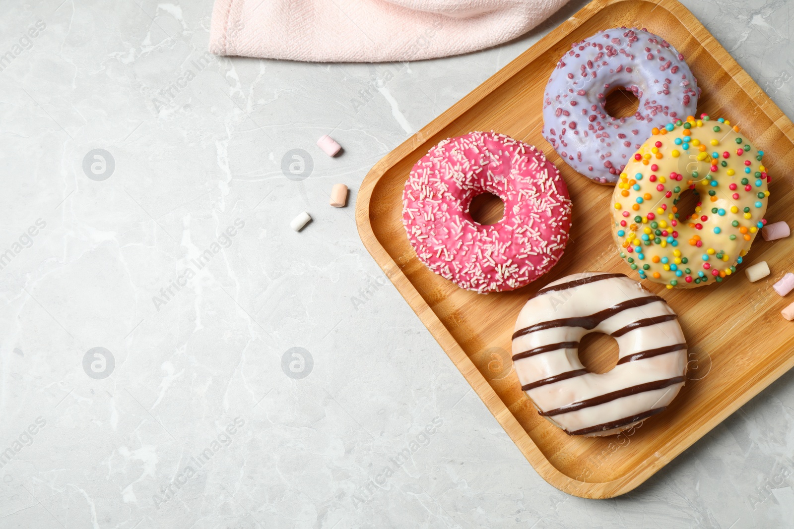 Photo of Yummy donuts with sprinkles on marble table, flat lay. Space for text