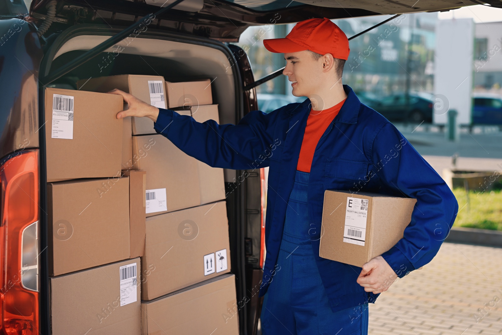 Photo of Courier with parcel near delivery van outdoors