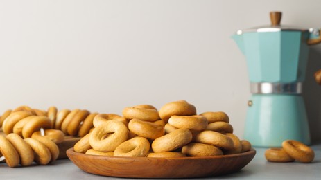 Photo of Plate with delicious ring shaped Sushki (dry bagels) on light grey table. Space for text