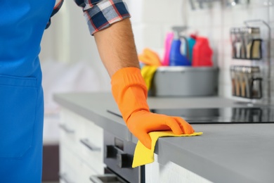 Photo of Man cleaning kitchen counter with rag, closeup