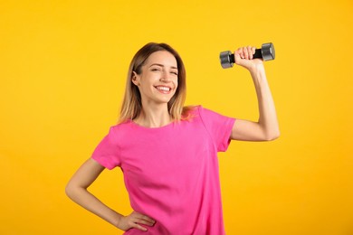 Photo of Woman with dumbbell as symbol of girl power on yellow background. 8 March concept