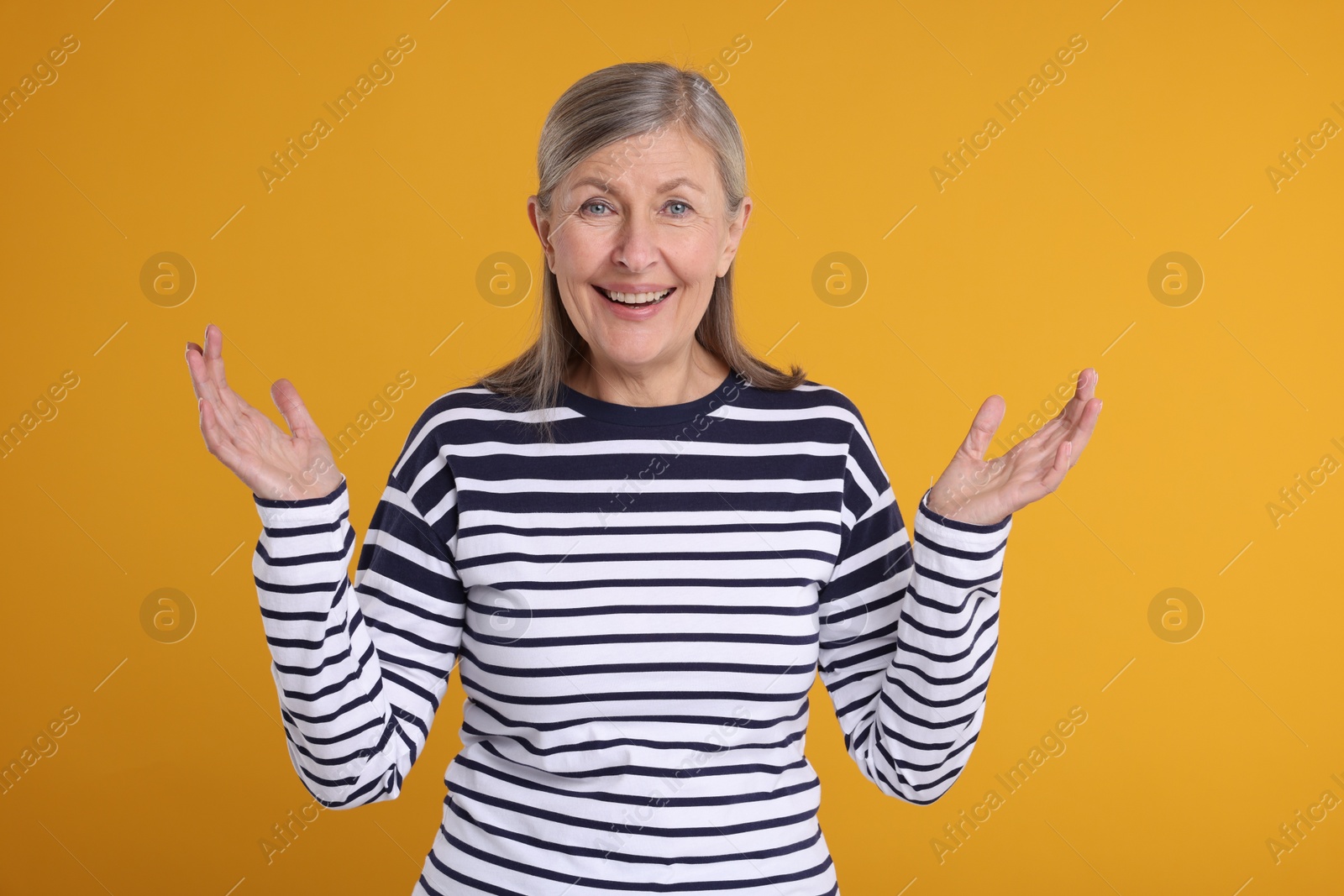 Photo of Portrait of happy surprised senior woman on yellow background