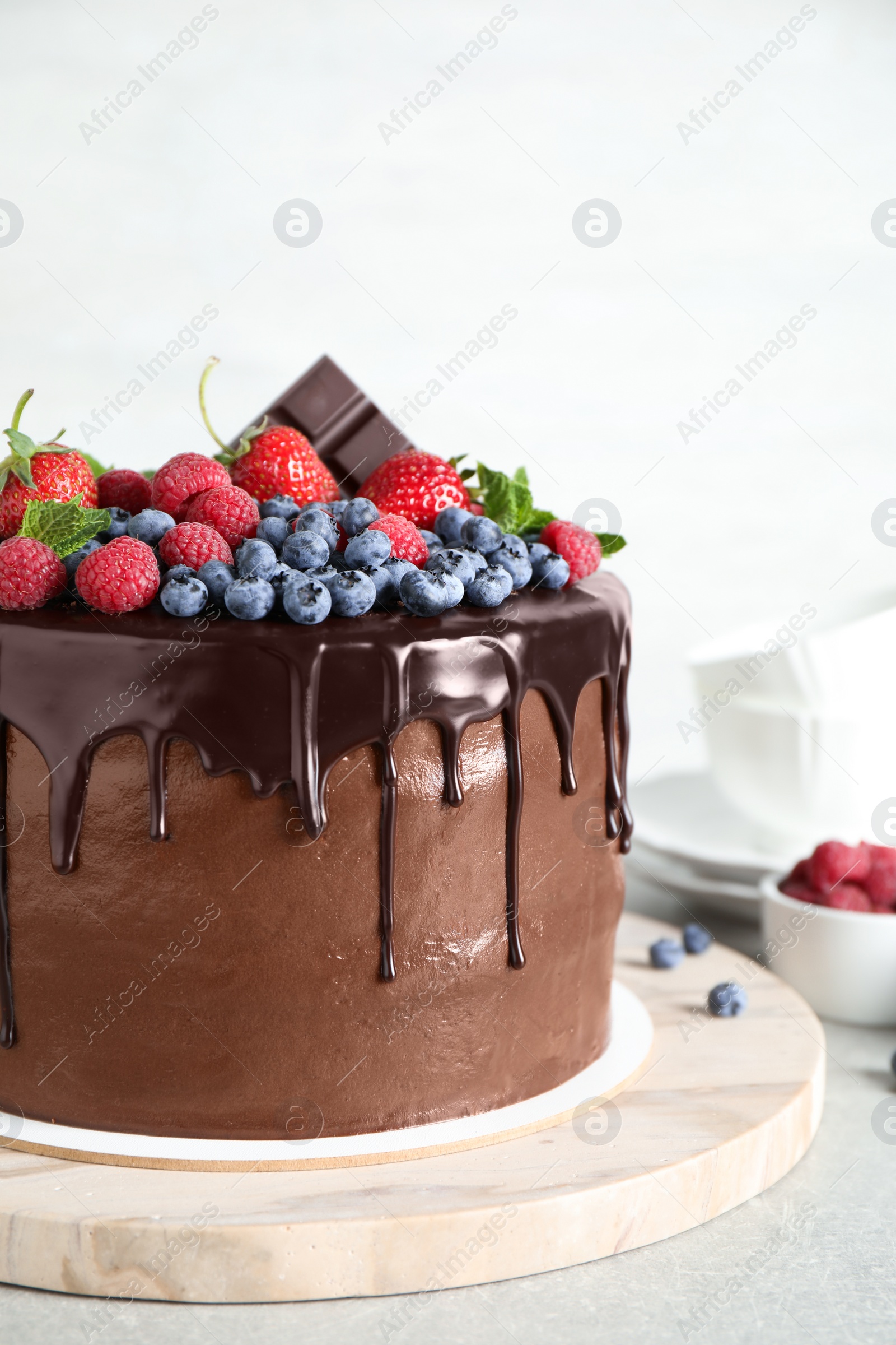 Photo of Freshly made delicious chocolate cake decorated with berries on white table