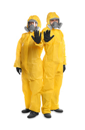 Photo of Man and woman in chemical protective suits making stop gesture on white background. Virus research