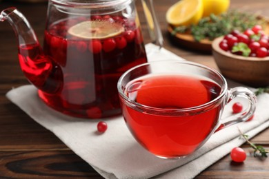 Photo of Tasty hot cranberry tea and fresh berries on wooden table