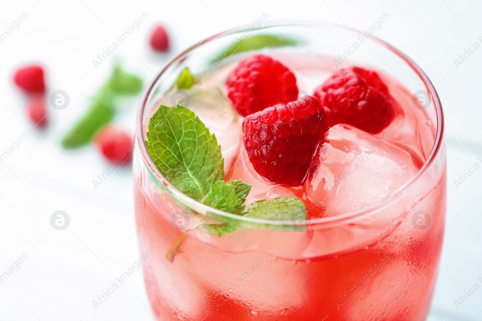 Photo of Glass of raspberry refreshing drink on table, closeup