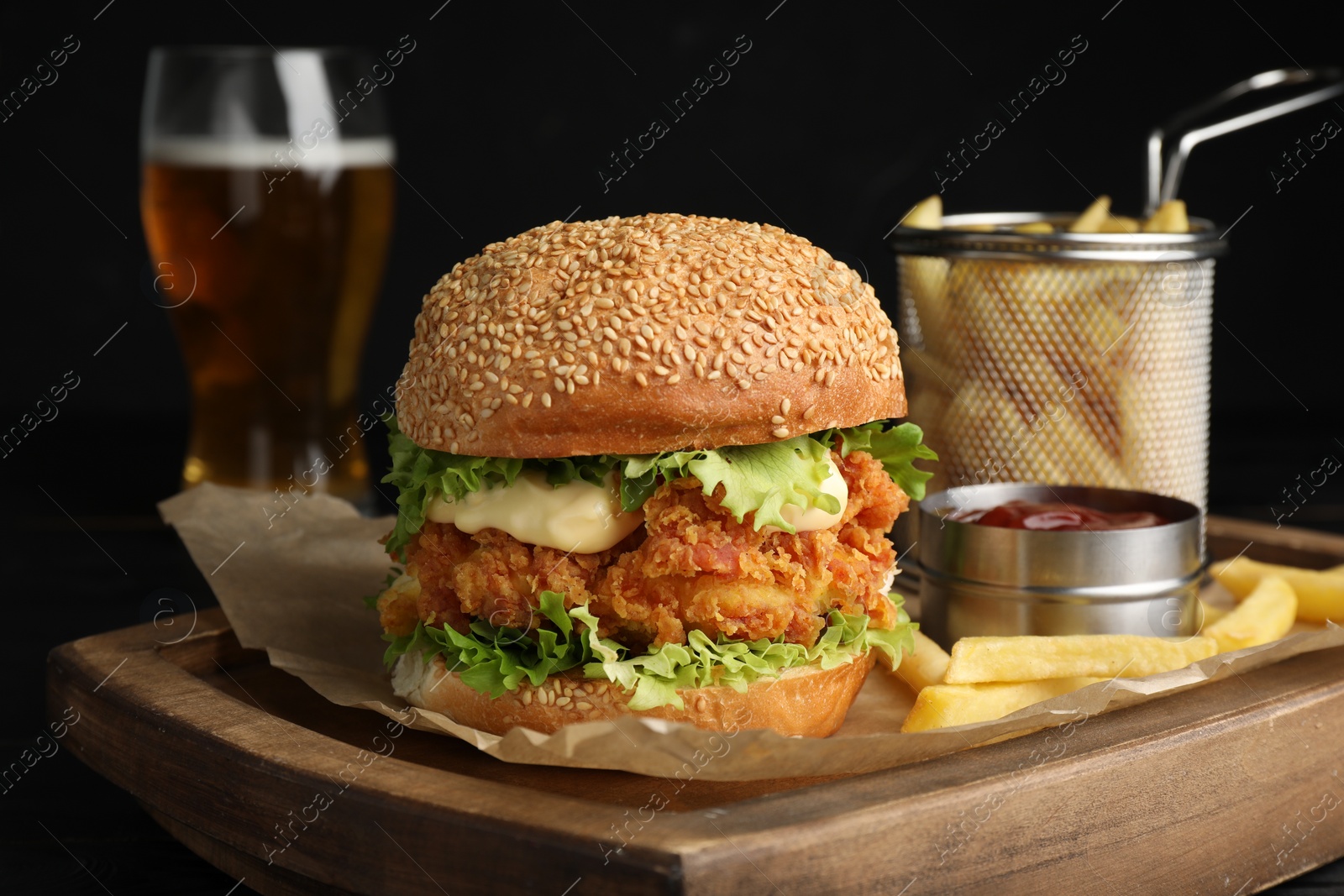 Photo of Delicious burger with crispy chicken patty, french fries and sauce on table