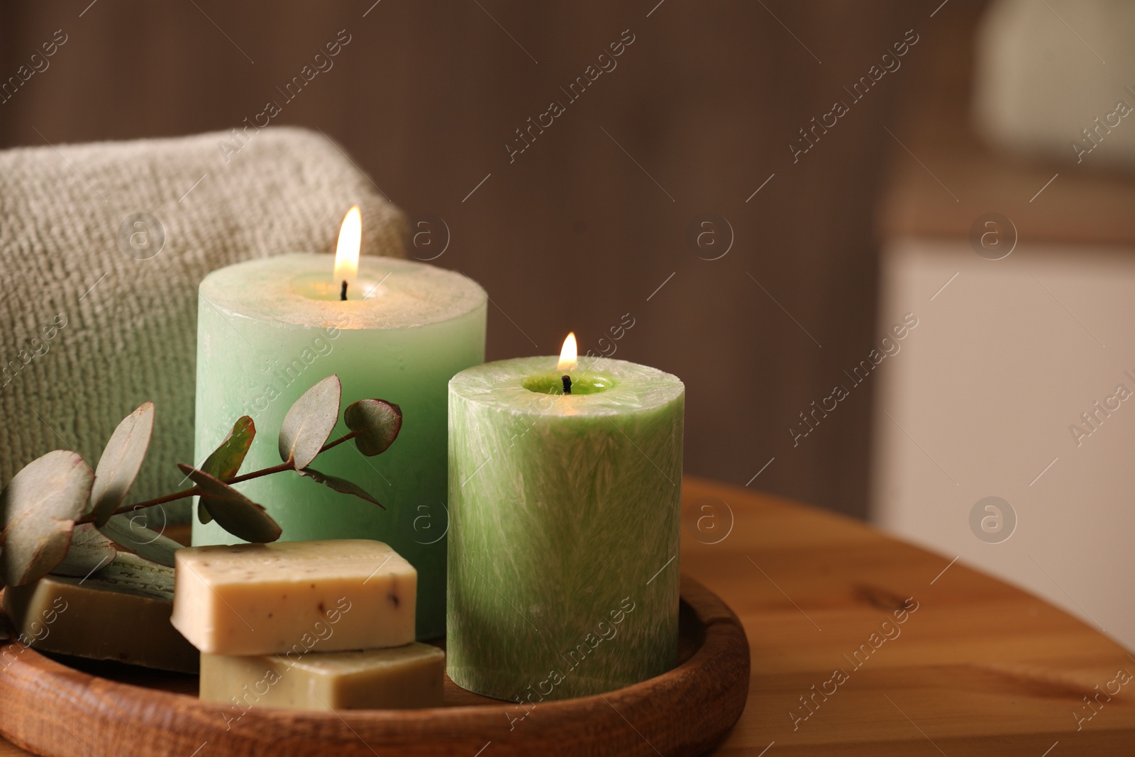 Photo of Spa composition. Burning candles, soap, towel and eucalyptus branch on wooden table, space for text