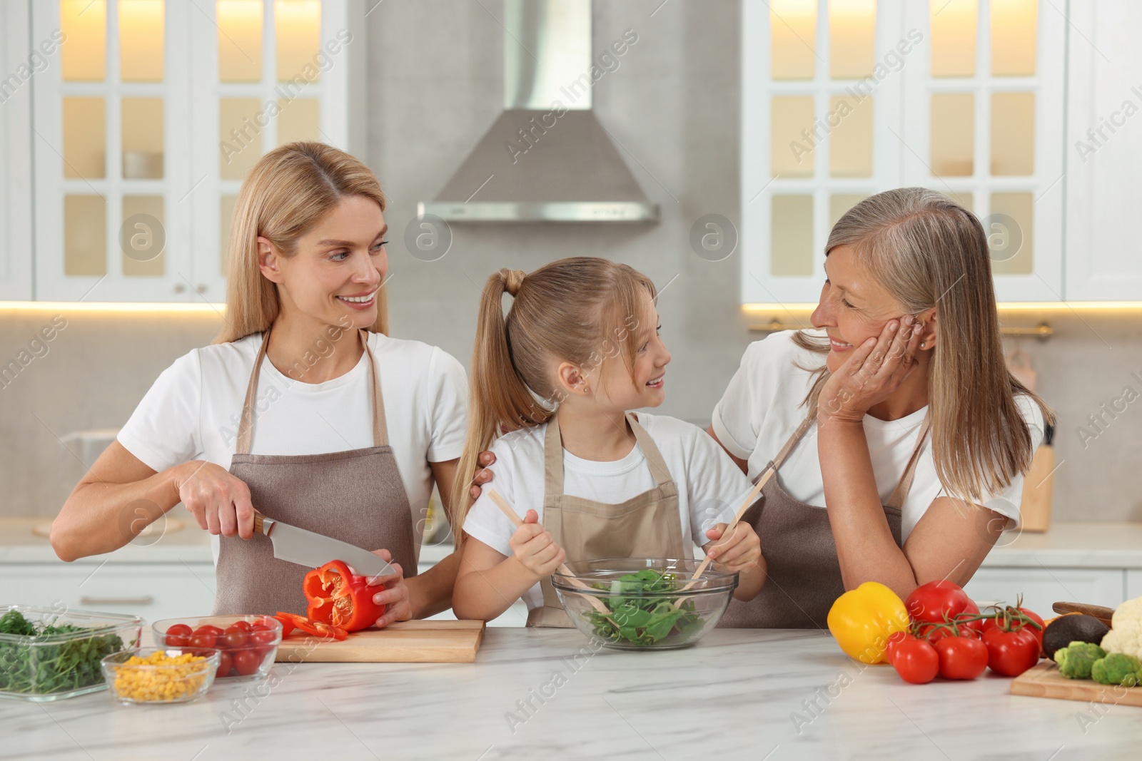 Photo of Three generations. Happy grandmother, her daughter and granddaughter cooking together in kitchen