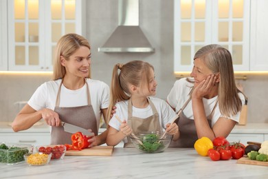 Three generations. Happy grandmother, her daughter and granddaughter cooking together in kitchen