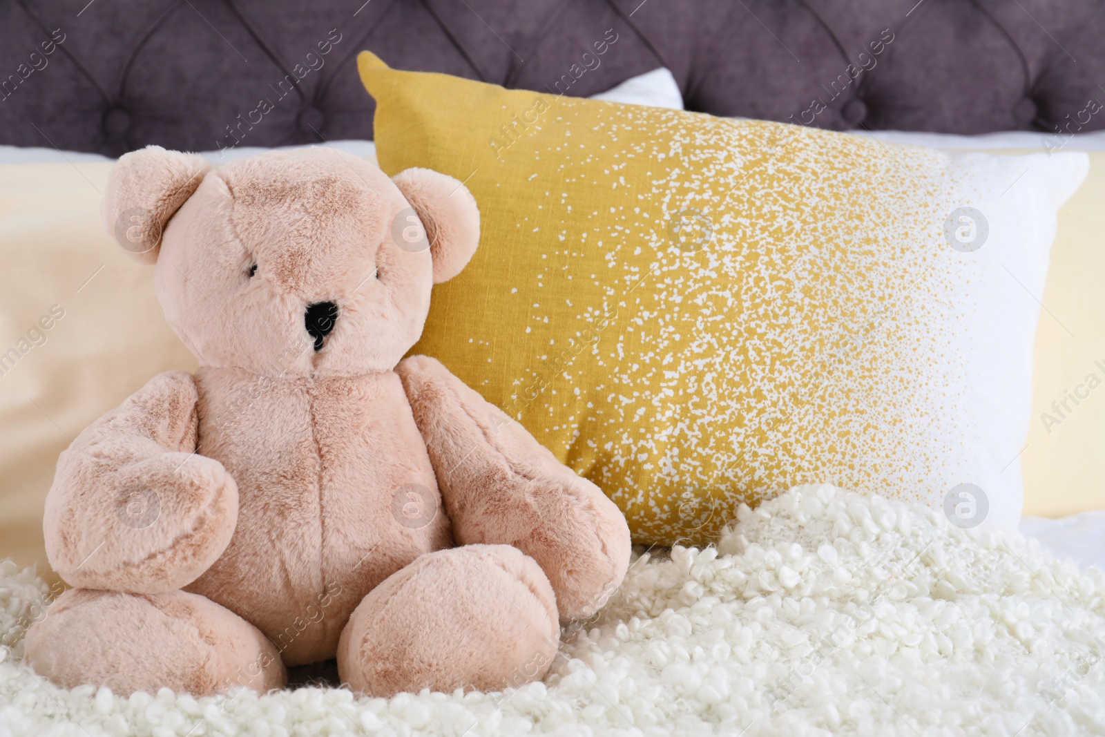 Photo of Cute teddy bear sitting on bed indoors. Space for text