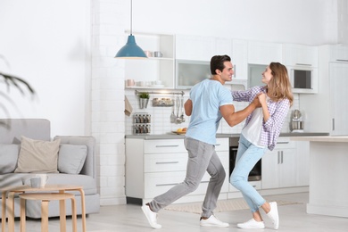 Photo of Beautiful young couple dancing in kitchen at home