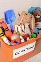 Photo of Donation box with different child toys on wooden table