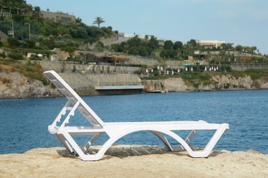 One lounge chair on beach near sea