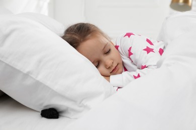 Photo of Cute little girl sleeping in bed, piece of coal under pillow. Saint Nicholas day tradition