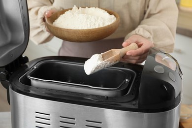 Photo of Making dough. Woman adding flour into breadmaker machine, closeup