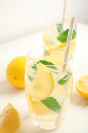 Photo of Cool freshly made lemonade and fruits on white wooden table