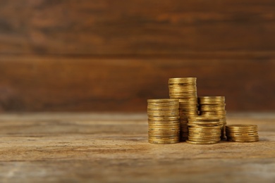 Many stacks of coins on table against wooden background, space for text