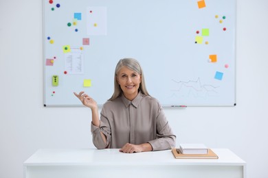 Happy professor giving lecture at desk in classroom