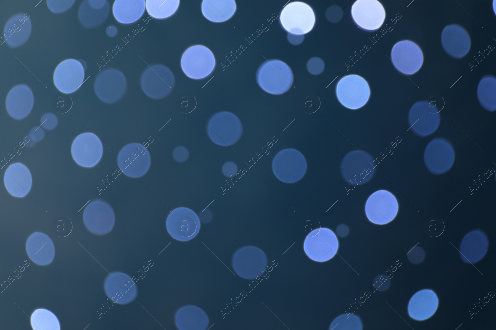 Photo of Blurred view of festive lights on blue background. Bokeh effect