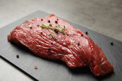 Photo of Fresh raw beef cut with thyme and peppers mix on grey table, closeup