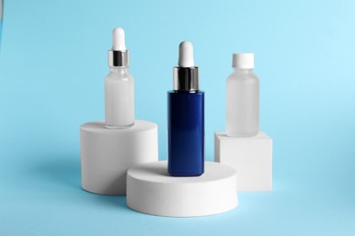 Bottles of cosmetic serum on light blue background