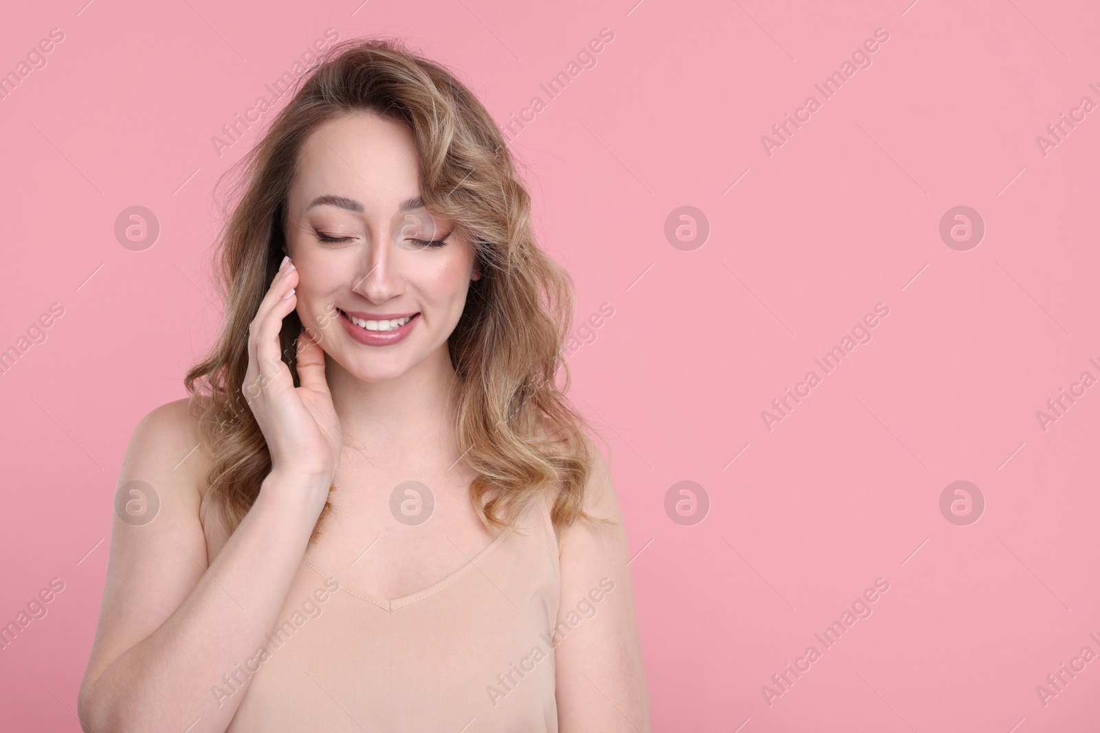 Photo of Portrait of smiling woman on pink background. Space for text