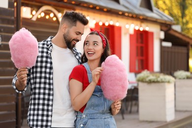 Photo of Happy couple with cotton candies spending time together outdoors