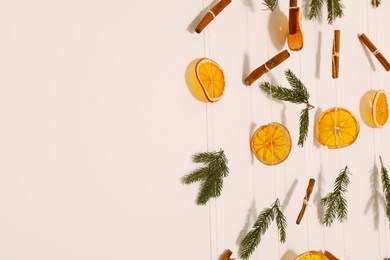 Handmade decor of dry orange slices, cinnamon sticks and fir tree branches on white wall, closeup. Space for text