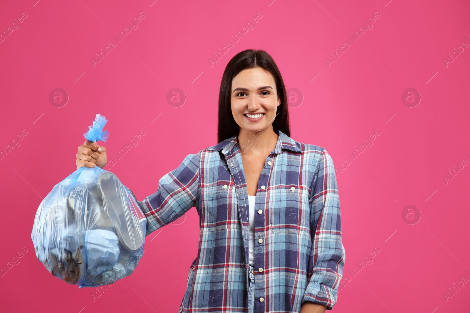 Photo of Woman holding full garbage bag on pink background