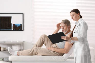 Photo of Professional female orthopedist consulting patient in clinic