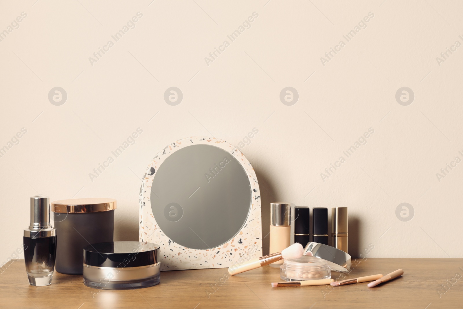 Photo of Mirror and makeup products on wooden dressing table near wall
