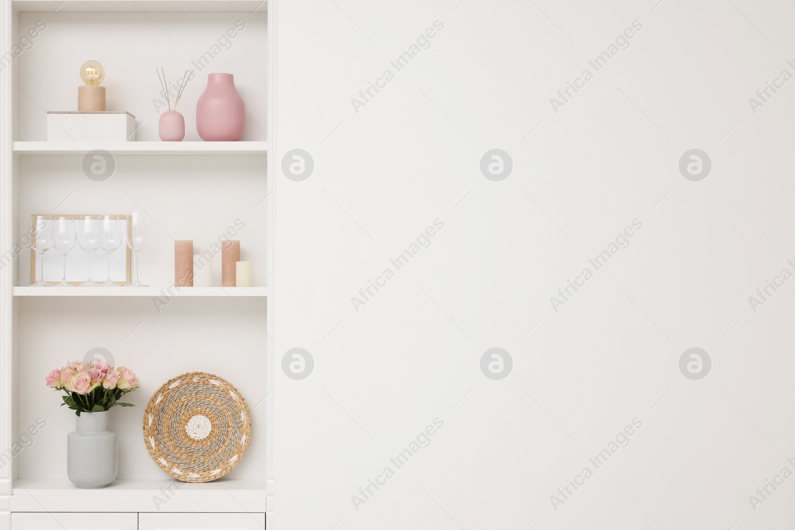 Photo of Shelves with different decor near white wall, space for text. Interior design