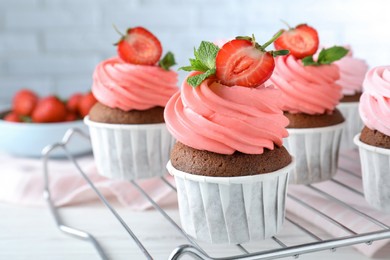 Photo of Delicious cupcakes with cream and strawberries on white table, closeup