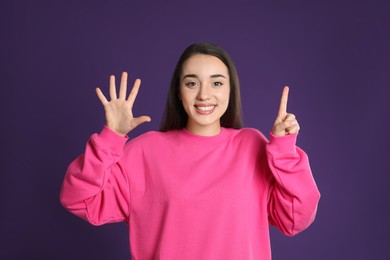 Photo of Woman showing number six with her hands on purple background