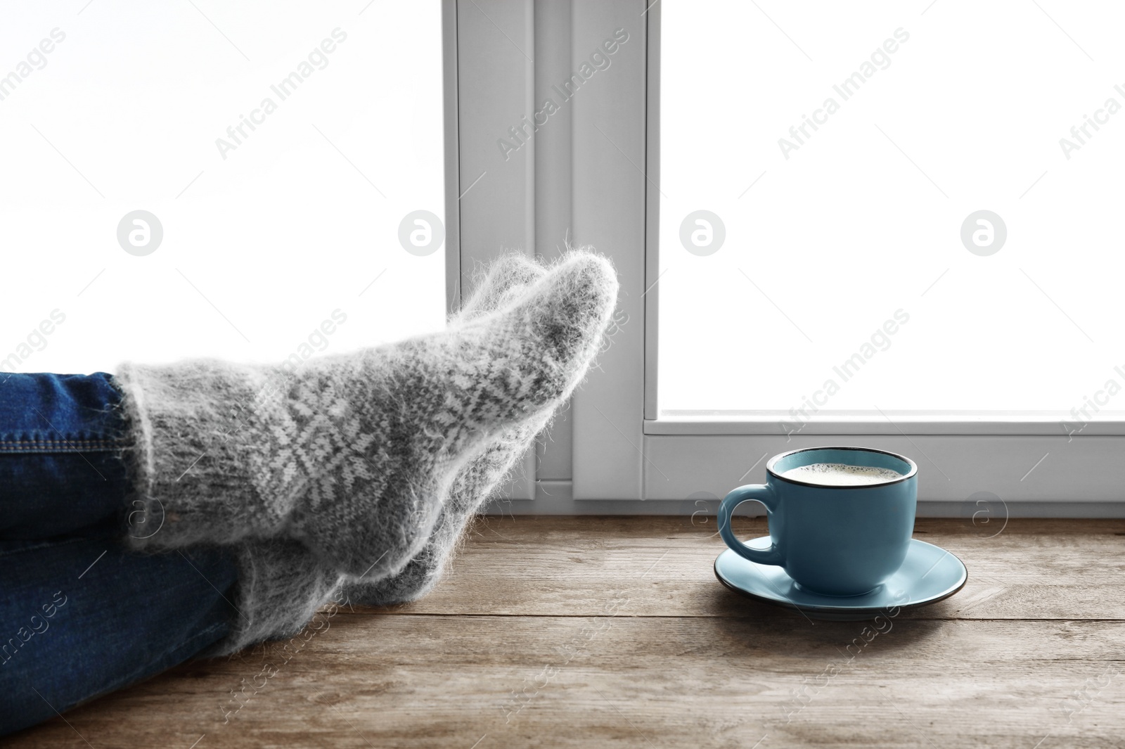 Photo of Woman in warm socks and cup of hot winter drink on windowsill. Cozy season