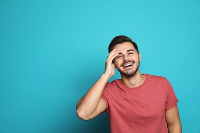 Photo of Handsome young man laughing against color background. Space for text