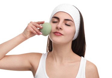 Photo of Young woman with headband washing her face using sponge on white background