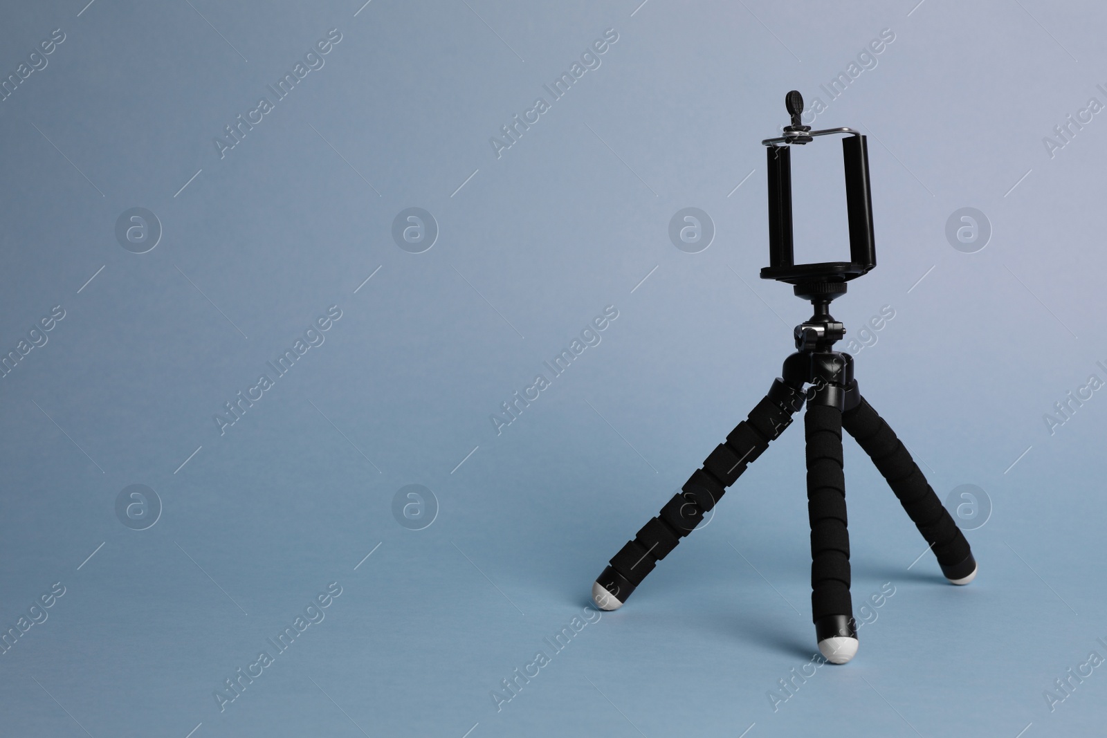Photo of Modern stylish mobile tripod on light blue background. Space for text