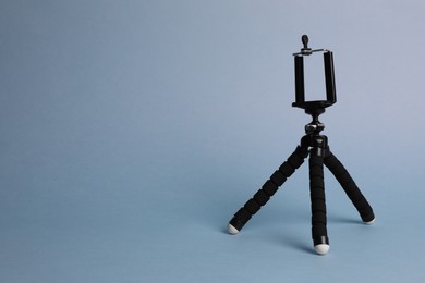 Modern stylish mobile tripod on light blue background. Space for text