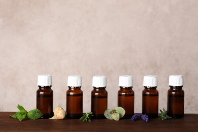 Photo of Glass bottles with different essential oils and ingredients on wooden table. Space for text