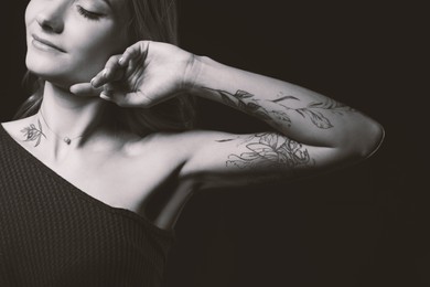 Image of Young woman with tattoo on dark background. Black and white photography